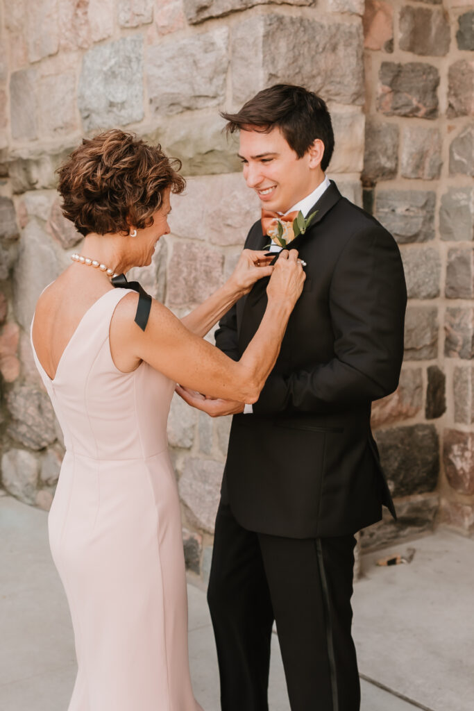 Mom pinning boutonniere on groom